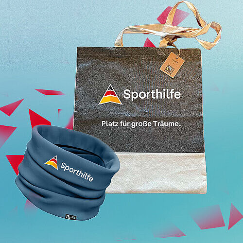Die Abbildung zeigt eine Tragetasche und einen dunkelblauen Schlauchschal mit Sporthilfe-Logo vor einem hellblauen Hintergrund. Rote geometrische Elemente setzen grafische Akzente, während der auf der Tasche sichtbare Schriftzug „Platz für große Träume.“ die Produktdarstellung ergänzt.