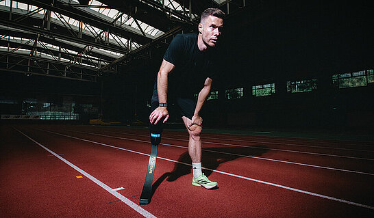 Die Aufnahme porträtiert eine Person mit einer Sportprothese in einer Leichtathletikhalle. Sie steht beispielhaft für Leistungsbereitschaft, individuelle Stärke und die Bedeutung von Rahmenbedingungen, die sportliche Teilhabe und Erfolg ermöglichen.