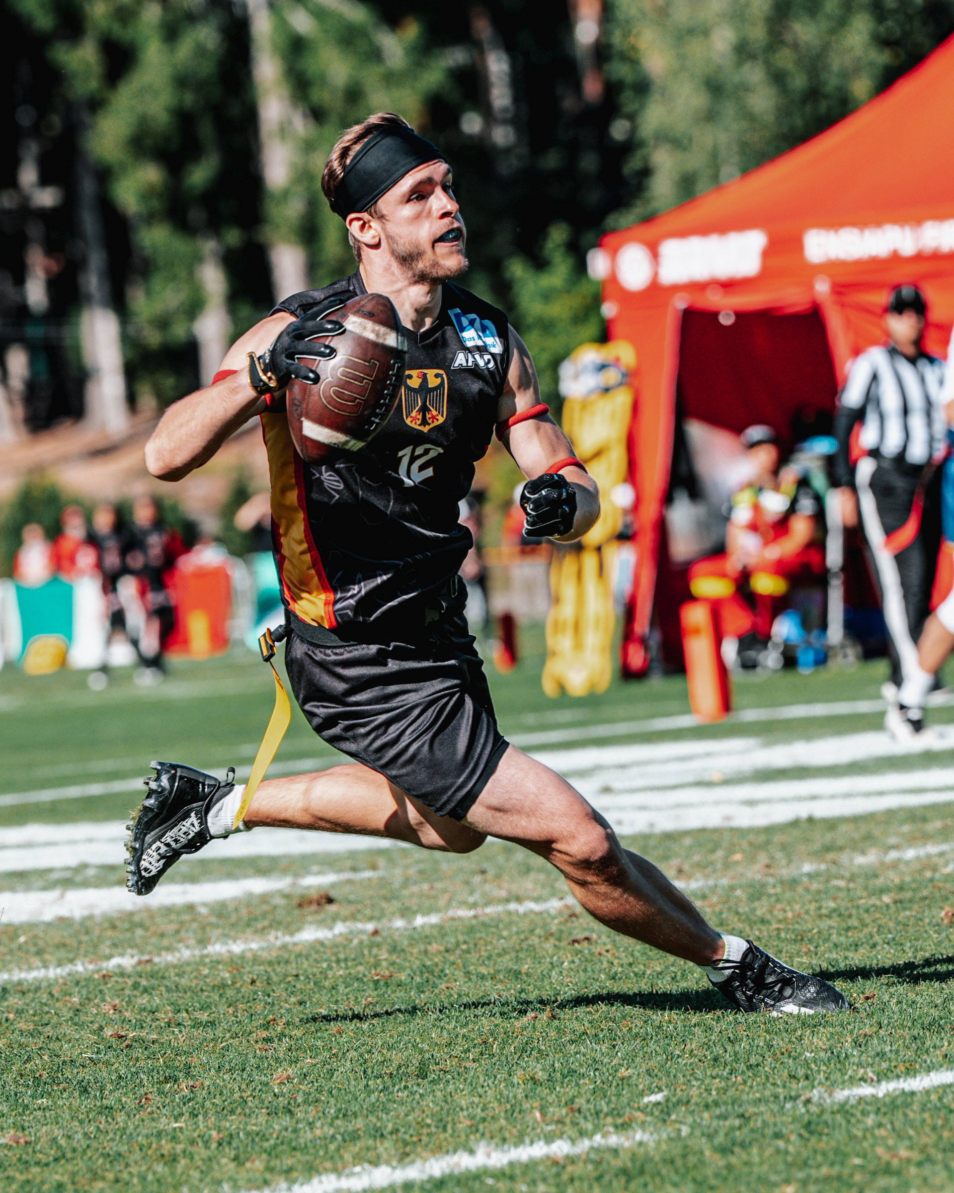 Flag Football-Spieler Moritz Apfel rennt im schwarzen Nationaltrikot mit einem Football in der Hand über das Spielfeld..